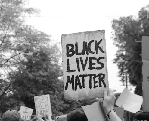 Black Lives Matter written on cardboard sign raised at a protest
