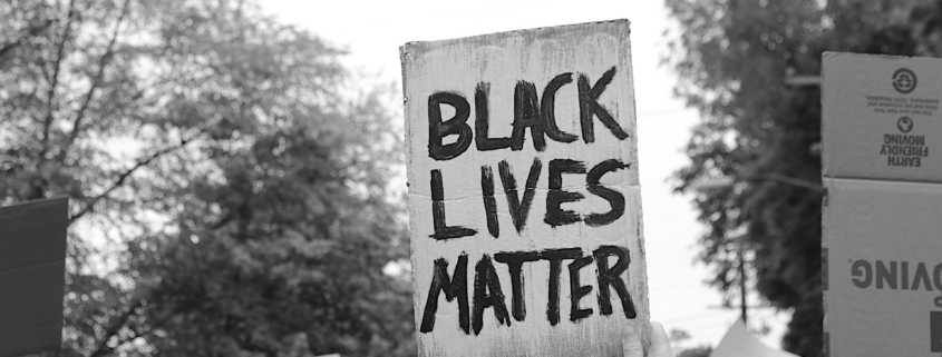 Black Lives Matter written on cardboard sign raised at a protest